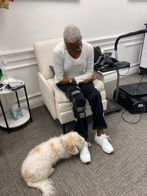 An older patient comfortably seated during in-clinic knee treatment.