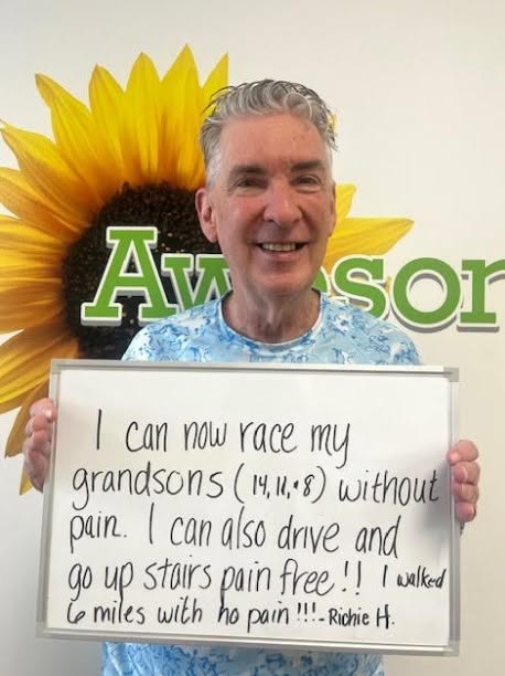 Richie H., a Vitality Healing Center patient, holding a handwritten whiteboard about racing his grandsons and walking without pain.